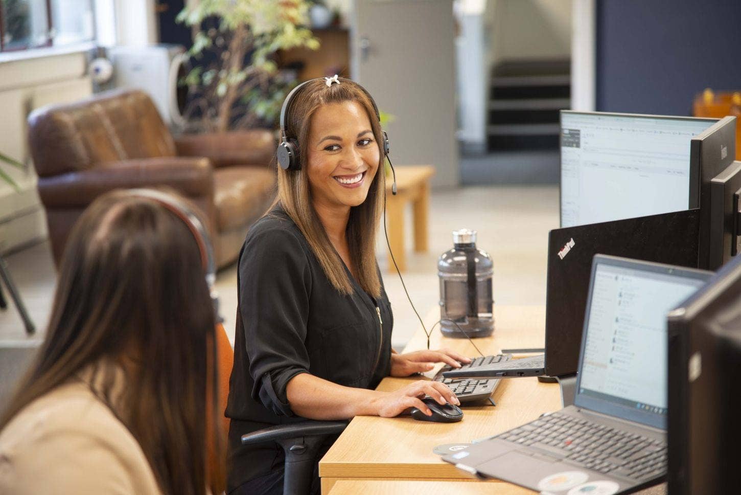 Customer service team member smiling on the phone to a customer.