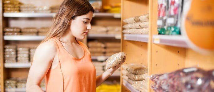woman in a shop looking at a food product and the food allergen labels on it