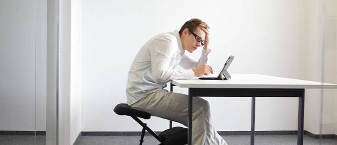 Employee at work hunching over at desk which could cause a musculoskeletal disorder