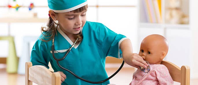 child role playing a doctor on a baby doll