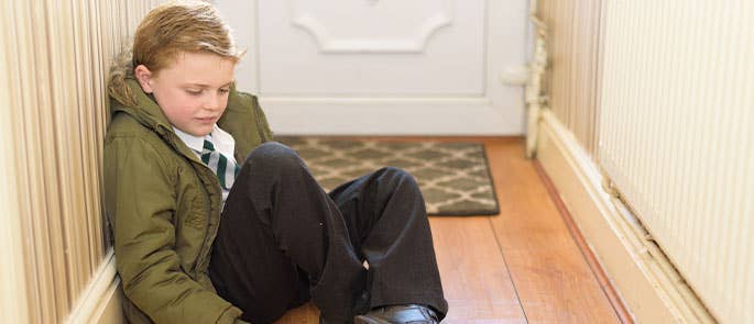 child at front door sad about going to school 