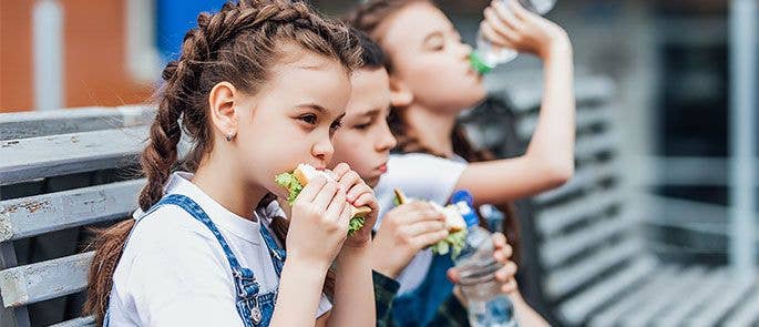 Children eating their lunch on a bench