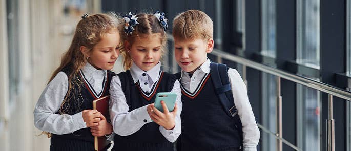 children gathered around a mobile phone in school 