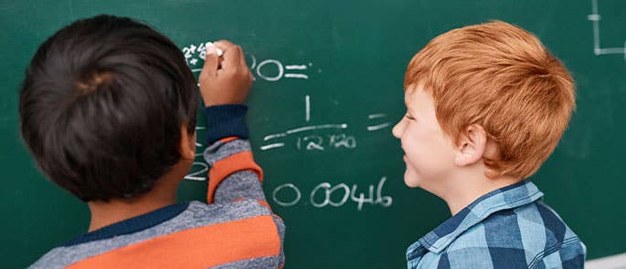 2 children solving a maths problem on a chalkboard